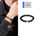 Men's black obsidian and silver bracelet with a 10mm prayer wheel charm on a dark background.