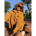 A man or woman wearing a loose-fitting yellow plaid cardigan-style shirt.