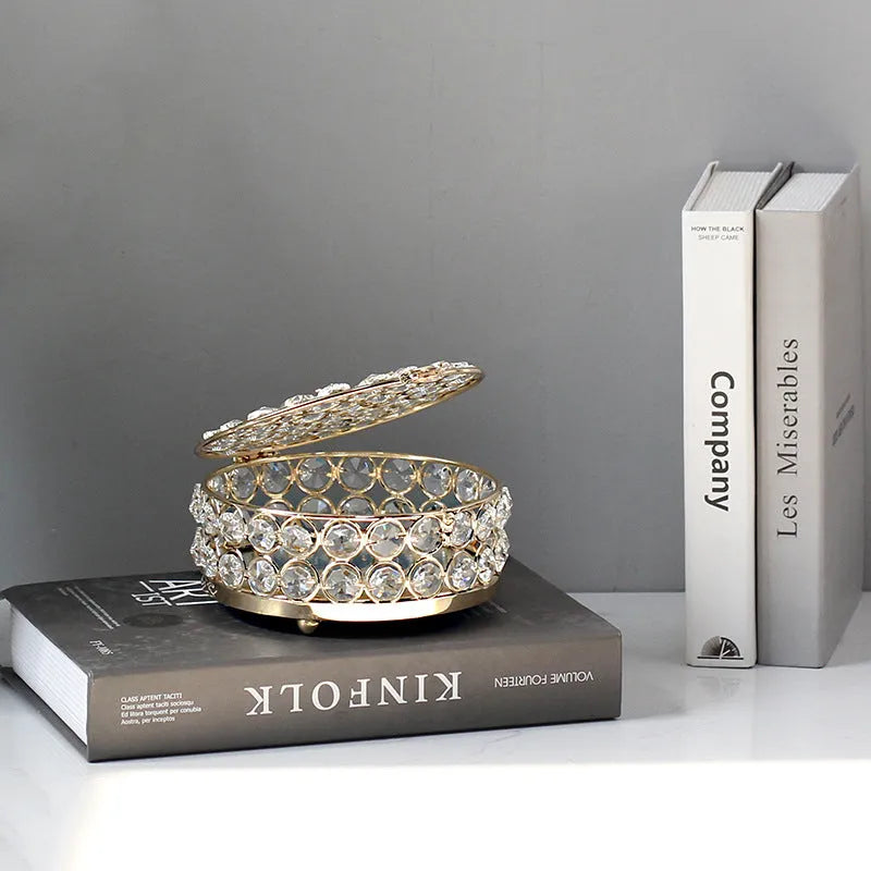 French gold iron jewellery box with a clear crystal glass lid on a wooden surface.