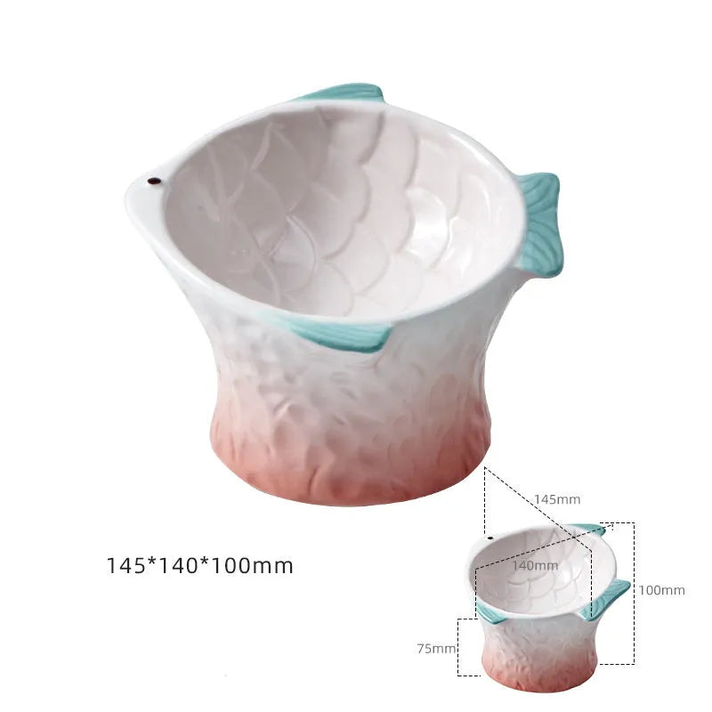 Blue ceramic cat food bowl in a fish shape with a tilted, elevated design and non-slip base.