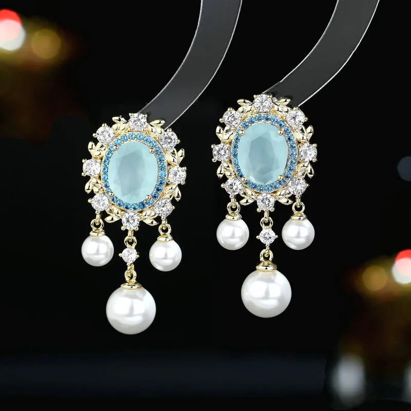 Oval-shaped copper drop earrings with inlaid zircon stones, white pearls, and a light purple tassel.