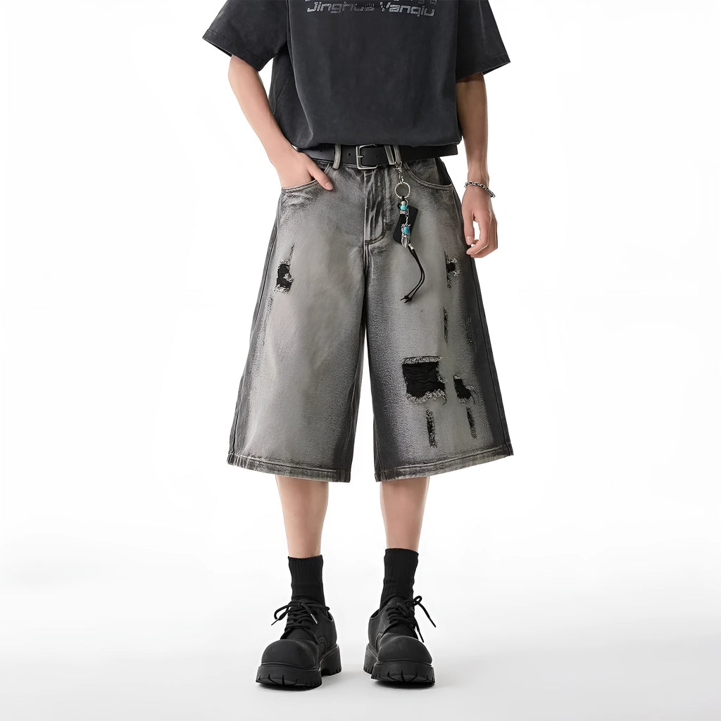 Grey distressed denim shorts with a loose cropped fit and hole details on a mannequin.
