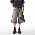 Grey distressed denim shorts with a loose cropped fit and hole details on a mannequin.
