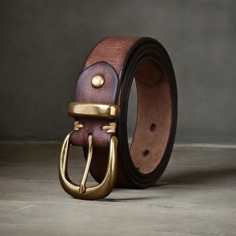 Men's black casual leather belt with a copper pin buckle on a jeans background.