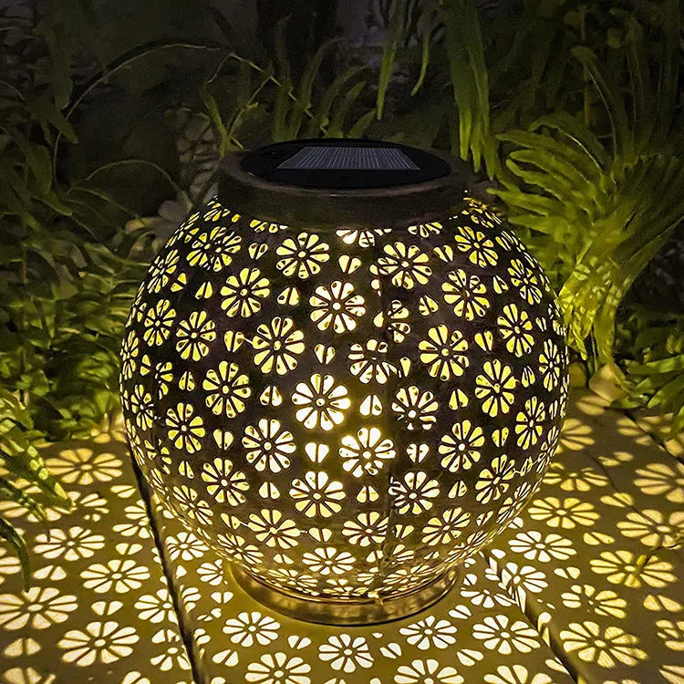 Solar wrought iron hollow flower projection lamp with warm white LED light and shadow pattern on grass