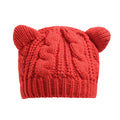 Hand-made red knitted beanie with 3D cat ears on a white background