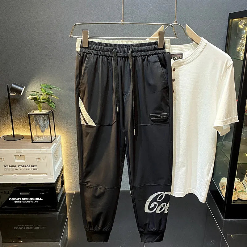Men's black ice silk cropped ankle banded trousers on hanger showing thin fabric and banded ankle detail