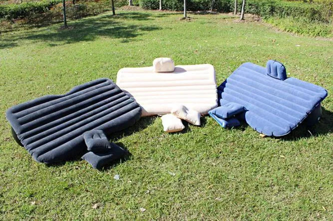 Inflatable car bed with flocked surface folded beside storage bag and two pillows