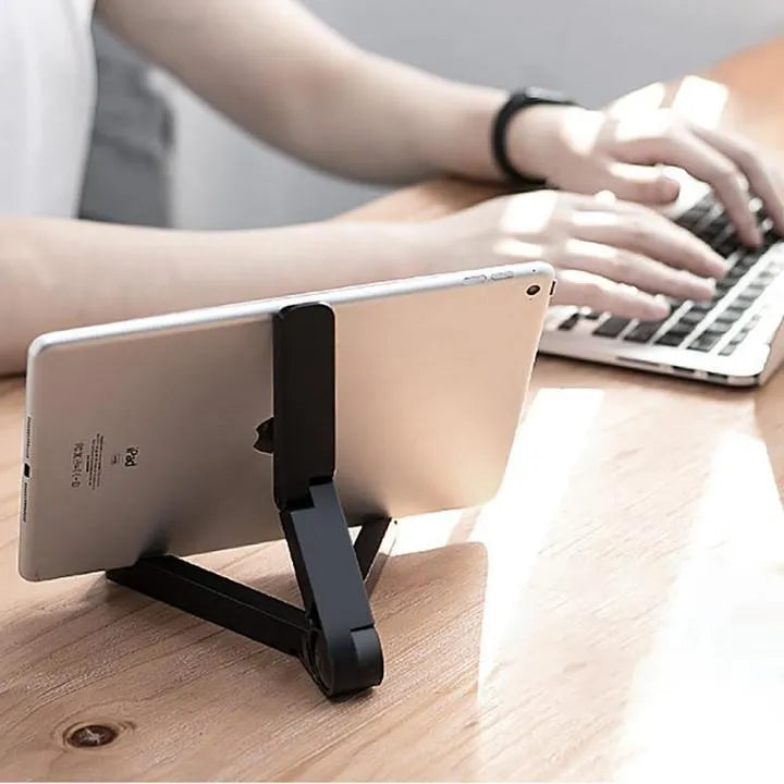 Black foldable tablet holder open on a table, holding a smartphone in landscape mode.