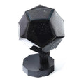 A white plastic LED star projector night light with remote control on a table.
