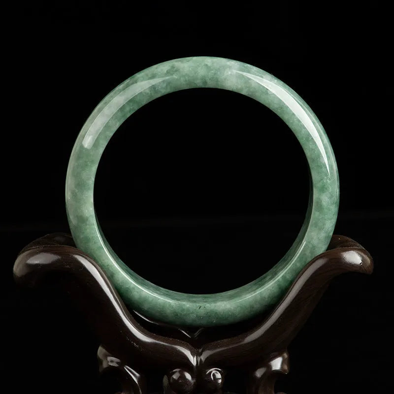 Natural emerald green jade bracelet on wrist, showing simple band style and deep pea green stone colour.