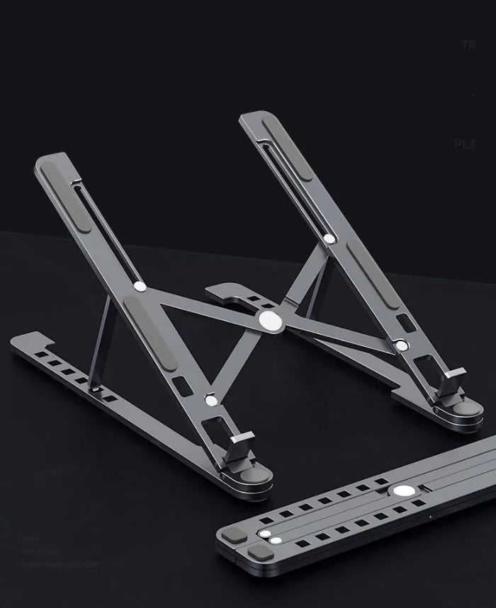 A folded deep grey aluminium laptop stand next to an open silver laptop on a desk.