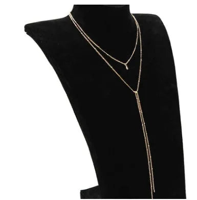 Multilayer lariat necklace in gold plated alloy on neutral background with visible 35cm and 45cm chain segments.