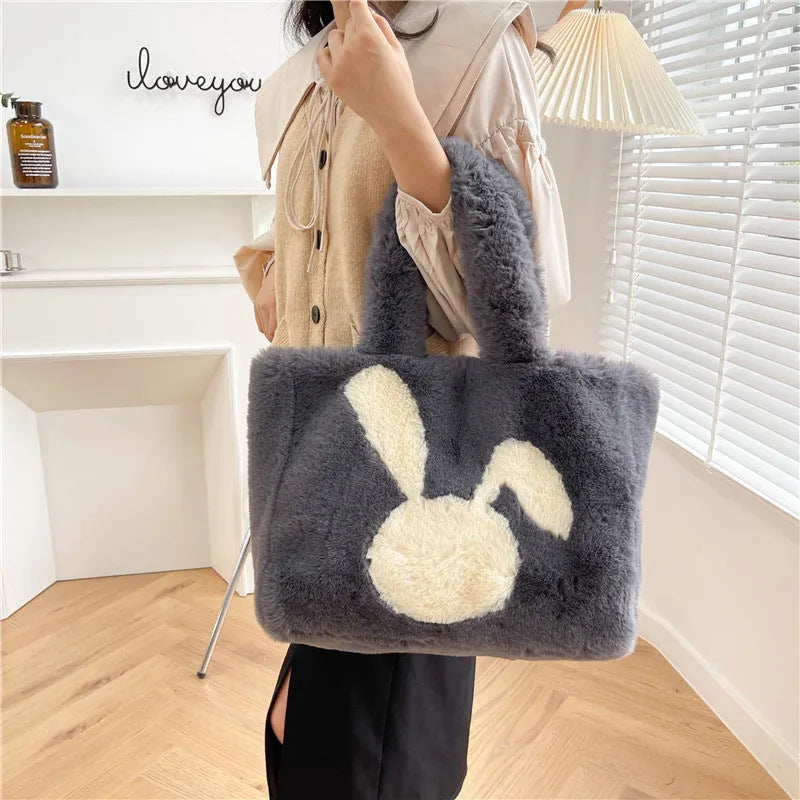 Plush shoulder bag with cartoon rabbit ears design in a solid colour.