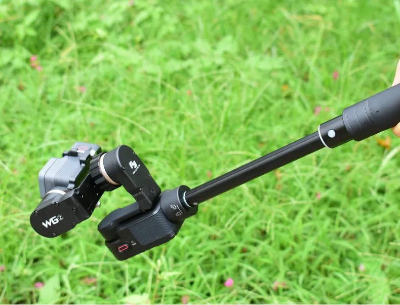 Black retractable selfie stick extended fully with phone attached, showing stabiliser grip.