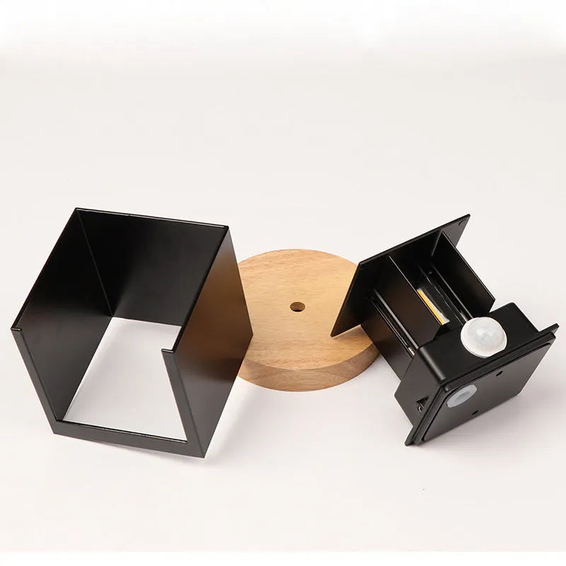 Square aluminium alloy wall lamp in black, mounted on a wall, showcasing its compact design and 360-degree light output.