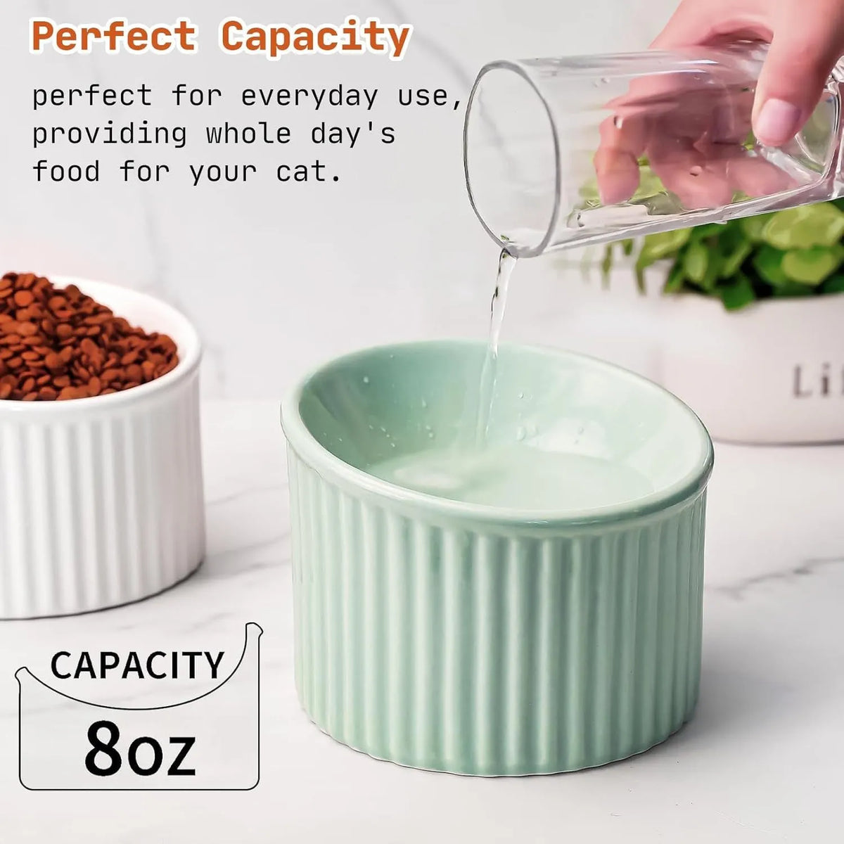 A dark green elevated ceramic cat bowl with a tilted, round design on a wooden surface.