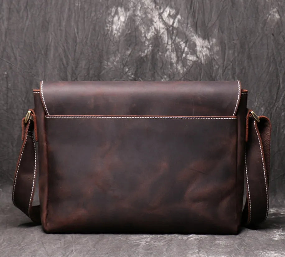 Vintage brown men's leather messenger bag showing interior compartments and adjustable shoulder strap