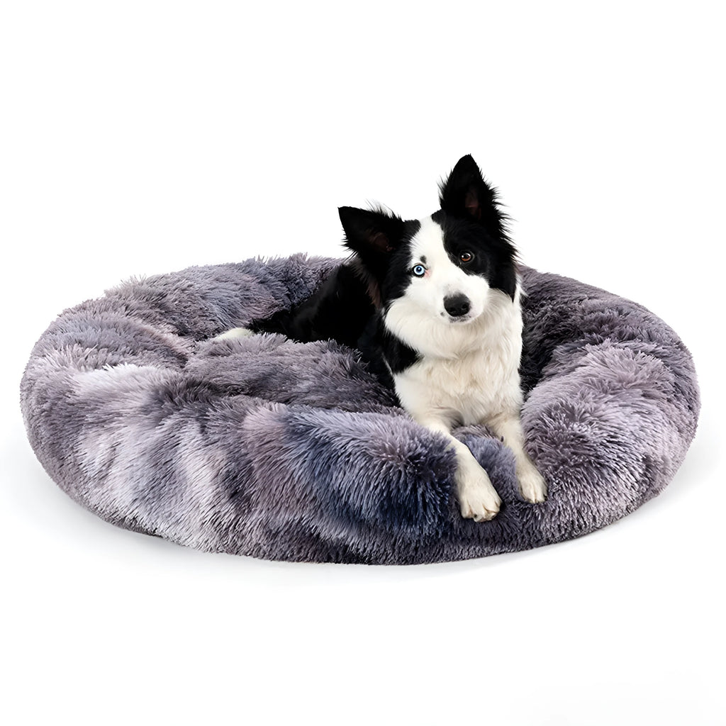 Fluffy grey donut-shaped dog bed with raised plush edge on a wooden floor.