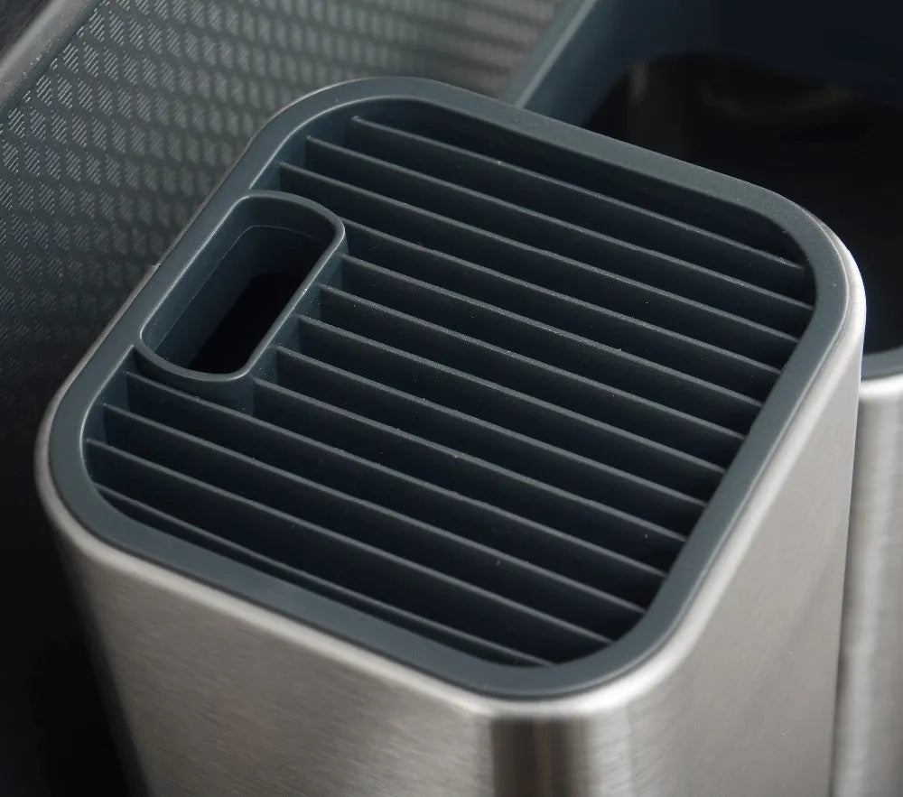 Black stainless steel kitchen tool holder with detachable base next to knives and cutlery