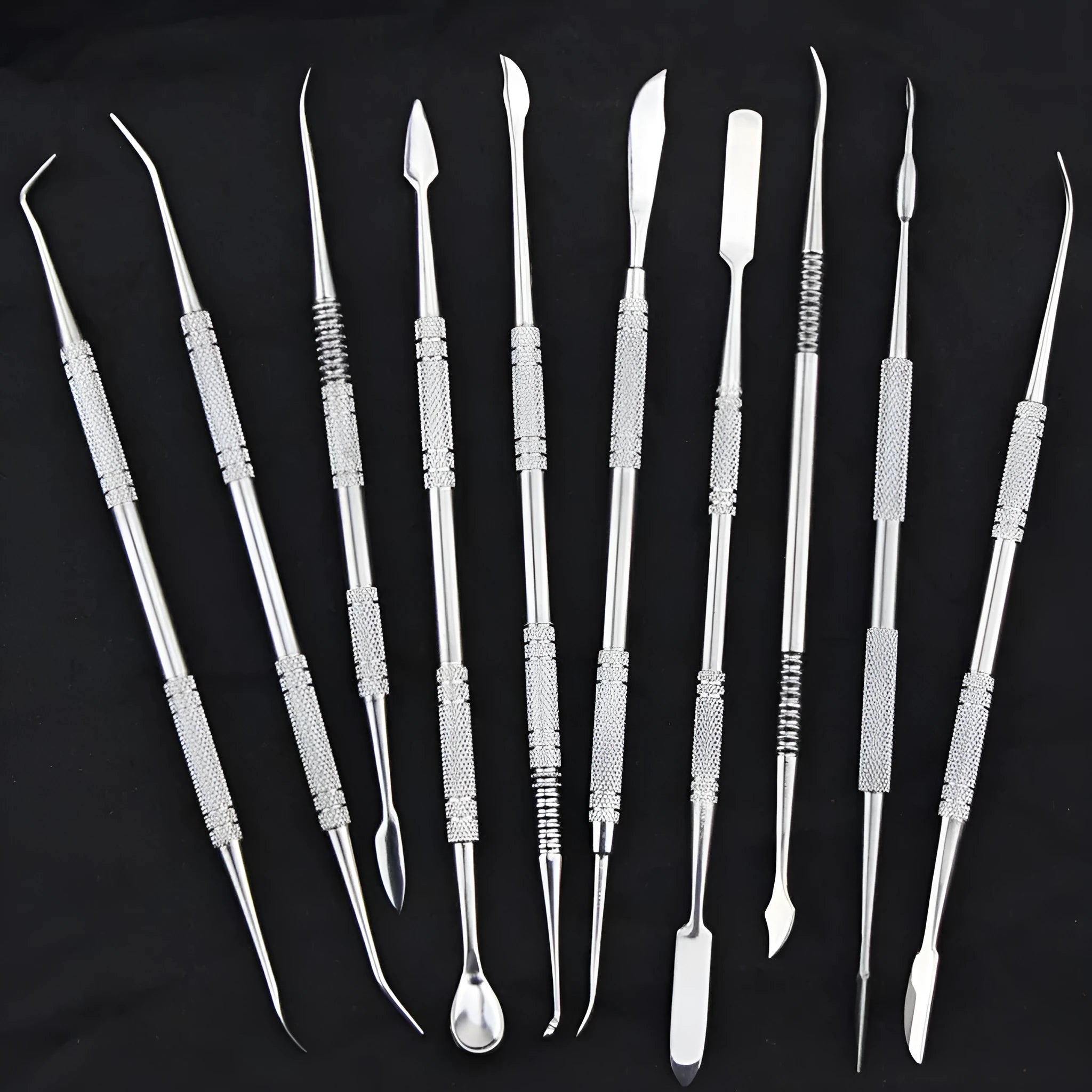 Ten stainless steel clay knives with photo colour handles arranged on a surface for pottery sculpting work.