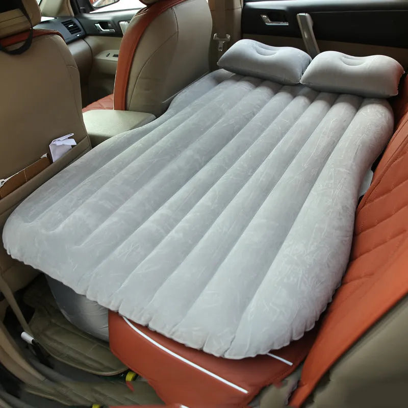Inflatable car bed with flocked surface folded beside storage bag and two pillows