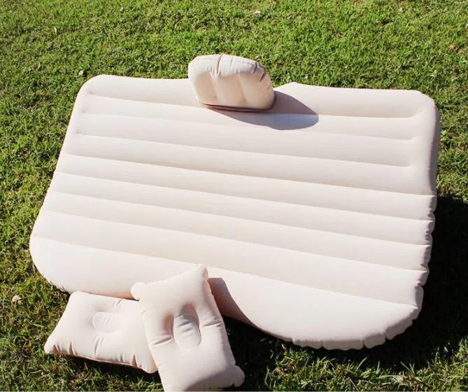 Inflatable car bed with flocked surface folded beside storage bag and two pillows