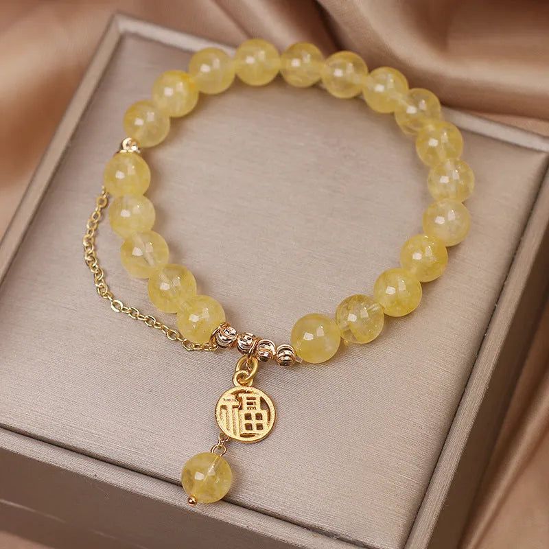 Close-up of a women's natural citrine bracelet with an electroplated Chinese character tassel.
