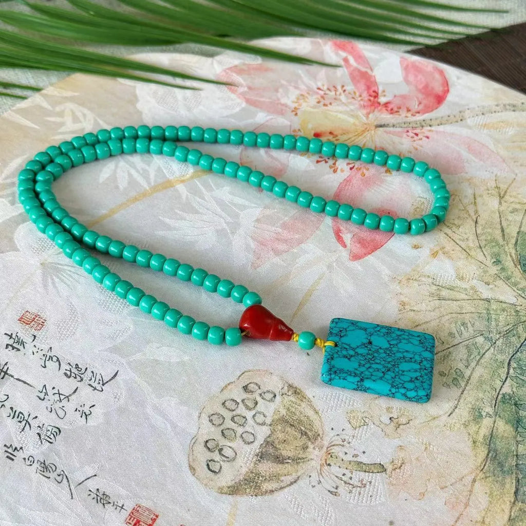 Turquoise mesh flower lucky pendant necklace with adjustable ball bead chain on display