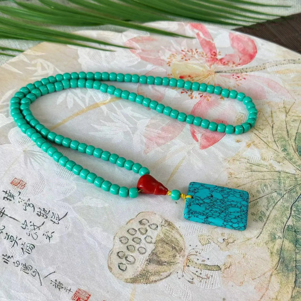 Turquoise mesh flower lucky pendant necklace with adjustable ball bead chain on display