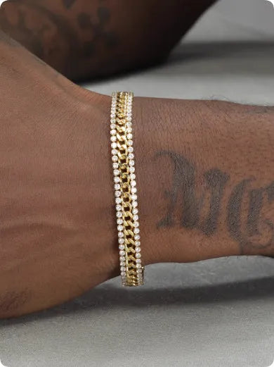 Gold coloured hip hop style tennis bracelet with chain links and artificial gemstone inlays on a wrist.