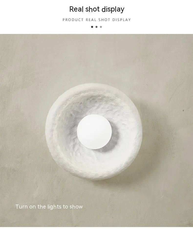 Japanese-style simple silent wall lamp with white resin shade in a modern room setting.