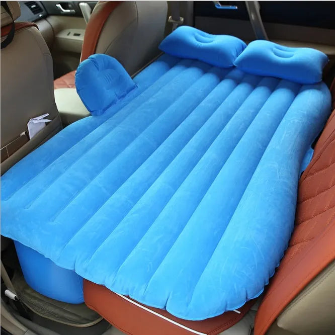 Inflatable car bed with flocked surface folded beside storage bag and two pillows