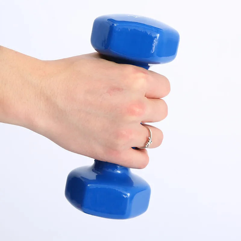 Bright green and pink plastic fitness dumbbells with glossy finish on a wooden floor.