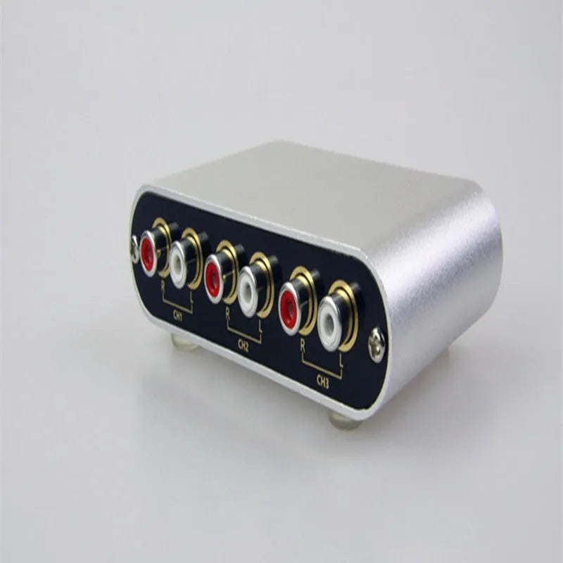Silver aluminium audio source switch unit with front-panel buttons and infrared remote control.
