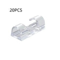 Transparent self-adhesive plastic wire holder snap clips for cable management on a white surface.