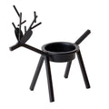 Black iron Christmas candlestick holder with decorative elk design on a festive table.