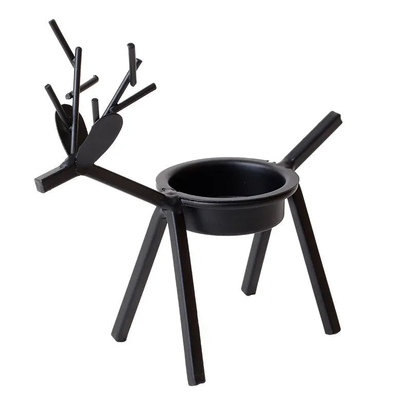 Black iron Christmas candlestick holder with decorative elk design on a festive table.