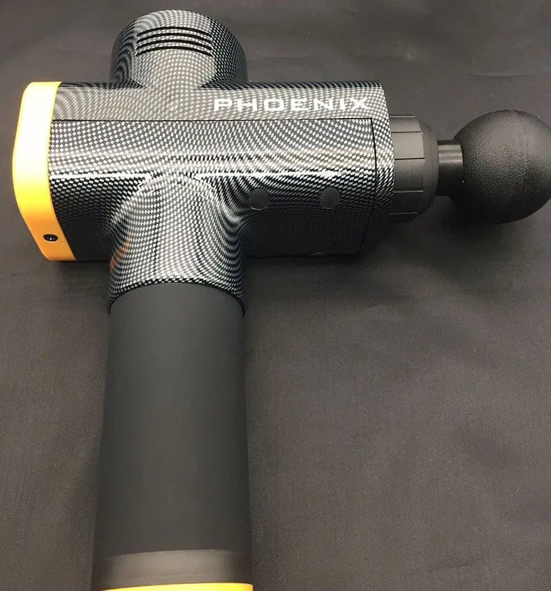 Black fascia massage gun with four different coloured massage heads on a table