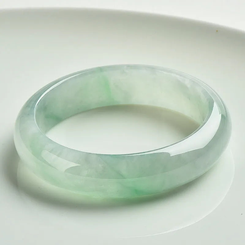 Natural light green jade bracelet with a metal clasp, shown on a wrist.