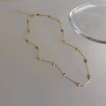 Square geometric clavicle chain necklace in gold tone with artificial crystal details on a white background.