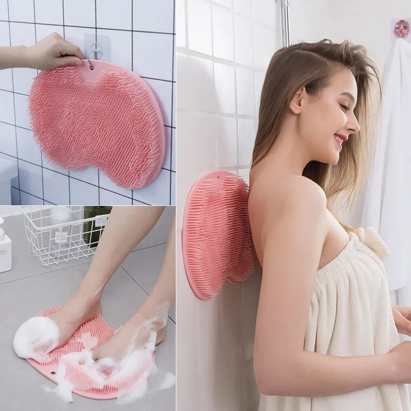 Orange silicone suction cup bath brush mat with bristles for foot and back cleaning on a bathroom floor.