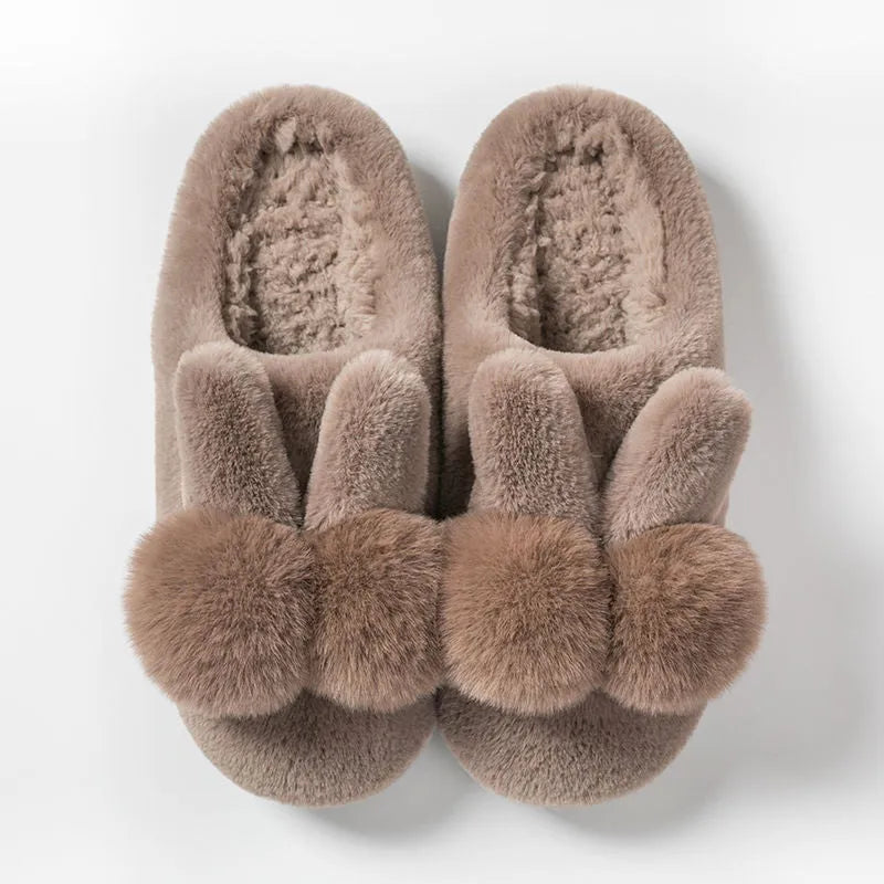Women's fluffy high-top rabbit fur slippers in cream colour on a wooden floor.