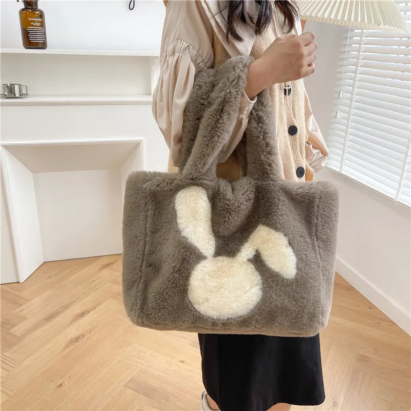 Plush shoulder bag with cartoon rabbit ears design in a solid colour.