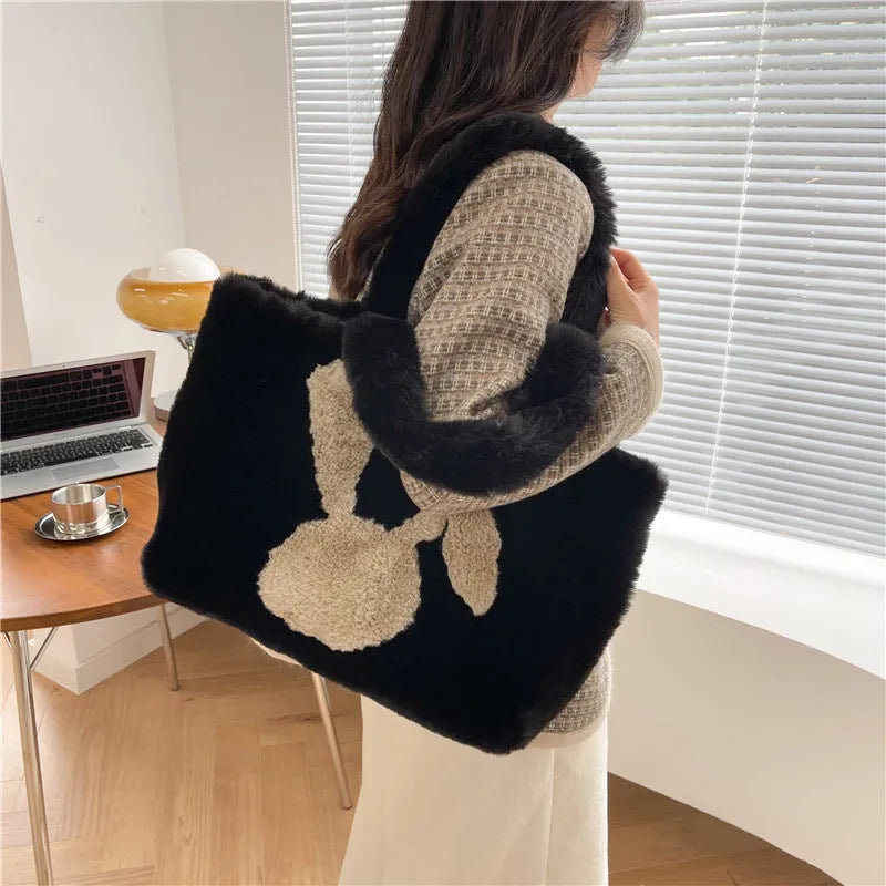 Plush shoulder bag with cartoon rabbit ears design in a solid colour.