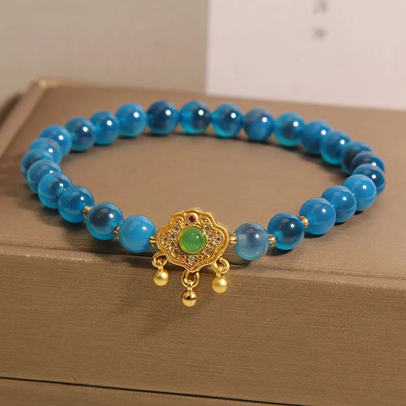 Close-up of a women's blue sugar heart agate safety lock pendant bracelet with crystal links and rhinestone detailing.