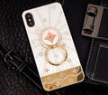 Rose gold diamond-shaped ring stand attached to the back of an iPhone, acting as a grip and phone stand.