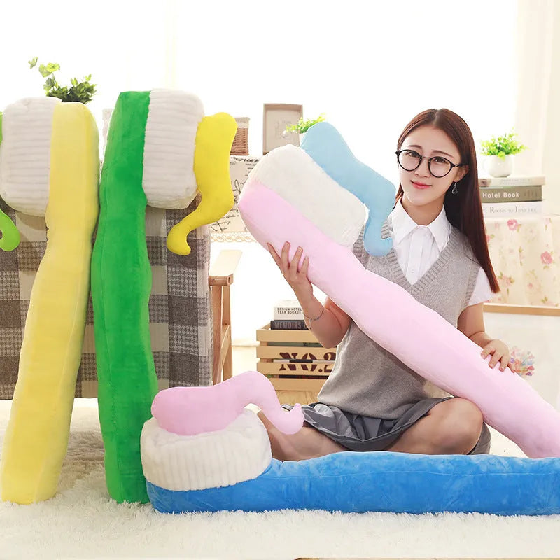 Cartoon toothbrush plush pillow 90cm in blue, green, pink, and yellow on a bed