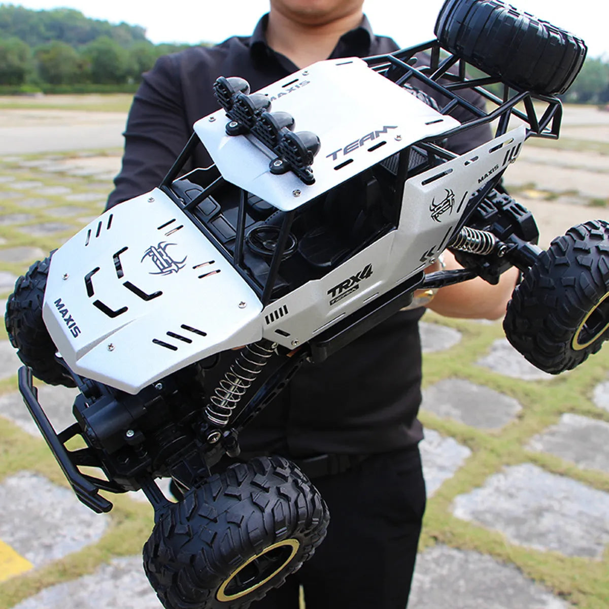 Black and silver 2.4G wireless remote control four-wheel drive car on a rough surface.