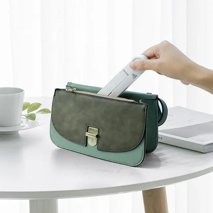 Black foldable tablet holder open on a table, holding a smartphone in landscape mode.